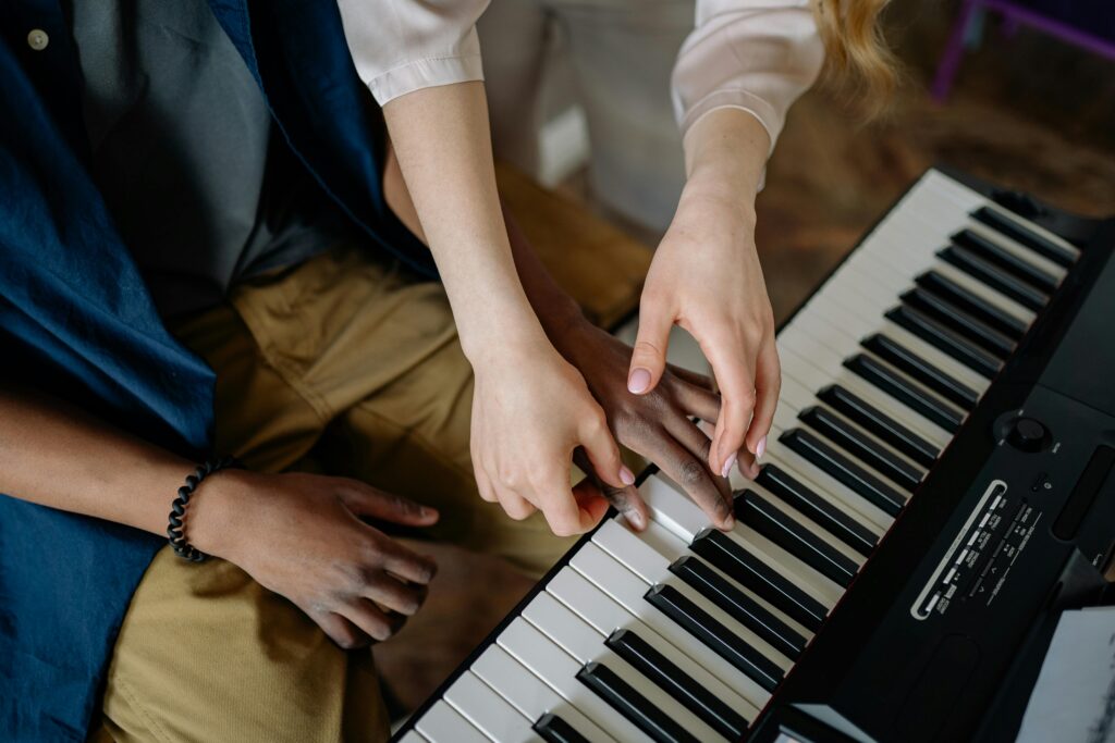 A detailed view of hands playing and teaching piano keys in an indoor setting.